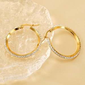 Detail of round gold-plated hoop earrings with sparkling cubic zirconia on glass tray