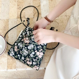 Close-up of floral crossbody bag with tiny pink flowers and adjustable black shoulder strap