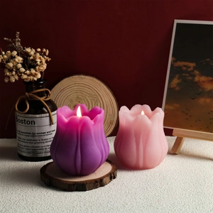 Vista dettagliata di candele profumate a forma di tulipano in viola e rosa su sfondo di stoffa