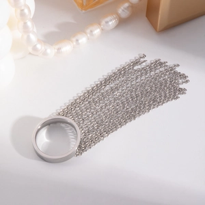 Silver fringe tassel chain ring with long dangling chains on a minimalist background