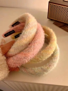 Gros plan de serre-têtes en peluche arc-en-ciel montrant la texture douce et le label fait main