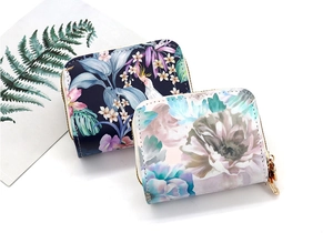 Detail view of multi-slot zipper wallets with tropical palm and peony floral patterns