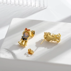 Elegant gold crown earrings with colorful zircon stones on white stone background