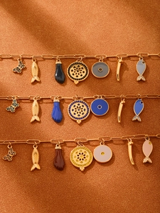 Detail of 18k gold plated bracelets with enamel charms on warm textured fabric