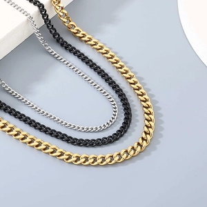 Detailed close-up showing three Cuban chain necklaces in gold, black, and silver steel
