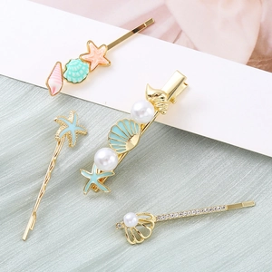 Golden starfish and shell hair clip set with pearls and rhinestones on green fabric