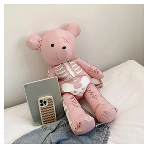 Detailed view of pink bear backpack with white gothic bone patterns on a soft bed
