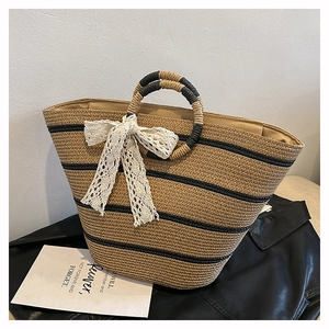 Détail du sac cabas en paille tissé avec rayures noires et nœud en dentelle blanche