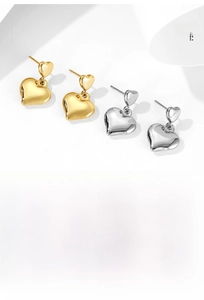 Detailed view of overlapping heart earrings in polished gold and silver metal finishes