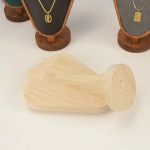 Detail of hand-shaped wooden jewelry holder with natural grain on a clean white surface