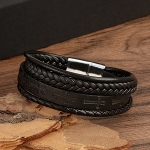Detailed view of black multi-layer woven leather bracelet with embossed cross magnetic clasp