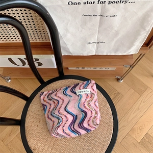 Detail of pink knitted makeup bag with rainbow wave patterns and minimalist brand label