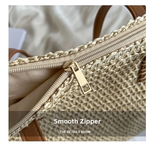 Close-up of a smooth gold metal zipper and brown leather handle on a straw woven bag