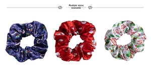 Detailed view of three festive satin scrunchies with Christmas snow and candy cane prints
