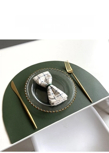 Macro shot of a semi-circular dark green leather placemat with lychee grain texture