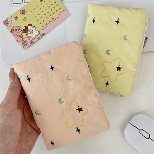 Detail of embroidered star and moon patterns on peach and yellow fabric passport bags