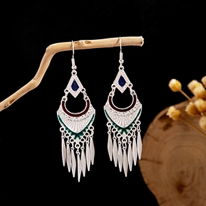 Detail of silver ethnic drop earrings with leaf tassels and blue enamel on a branch
