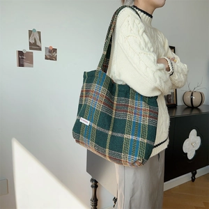 Detail of green plaid wool tote bag showing thick fabric texture and woven brand label