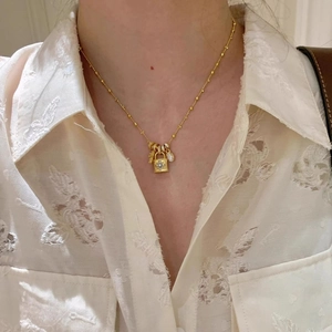 Golden necklace with cubic zirconia lock and key pendant worn on a white lace shirt