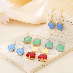 Collection of colorful oval glass earrings in assorted vibrant colors on stone display