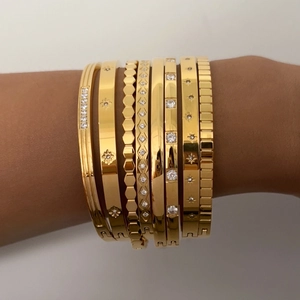 Detail of stacked gold bangles with starburst zircon and geometric motifs on wrist