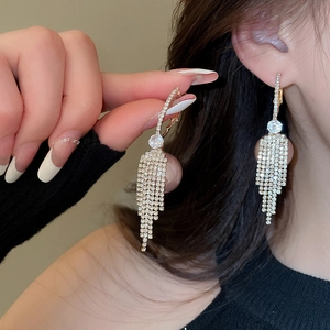 Close-up of model wearing gold long tassel earrings with sparkling rhinestones detail