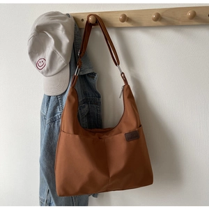 Detail of caramel nylon crescent bag hanging with denim jacket on a wooden rack