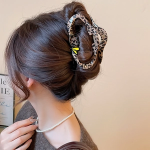 Detailed back view of a leopard print hair claw clip with cat and heart charms on a model