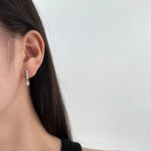 Detail shot of silver heart drop earrings with clear zircon stones on a model ear