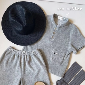 Dettaglio di un set casual in maglia grigia con cappello di paglia e calze
