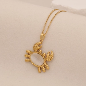 Gold crab pendant necklace with opal stone shell on a natural stone aesthetic background