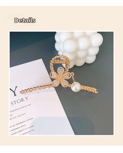 Detail of gold floral hair claw with twisted texture, sparkling crystals and pearl drop