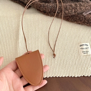 Detailed close-up of brown faux leather key pouch necklace with fine litchi grain texture