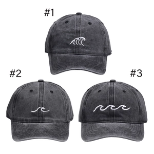 Detailed views of three washed charcoal baseball caps with unique wave embroidery designs