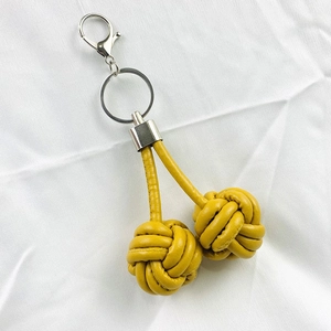Handmade yellow leather monkey fist knot keychain with silver metal clip on white fabric