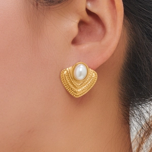 Detailed macro view of vintage gold plated earrings with white pearl inlay on model ear