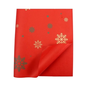 Papier cadeau de Noël rouge avec flocons dorés et verts sur fond blanc neutre