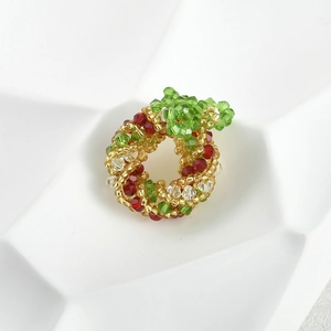 Macro detail of handmade beaded Christmas wreath charm in red and green crystal beads