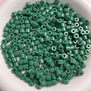 Vista macro di perle cilindriche in acrilico verde da 6mm per gioielli fatti a mano in ciotola