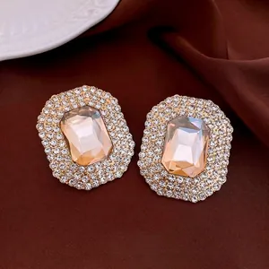 Champagne crystal rectangle stud earrings with rhinestone halo on brown silk fabric