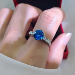 Detail of a luxury silver ring featuring a six-prong set deep blue round brilliant gemstone