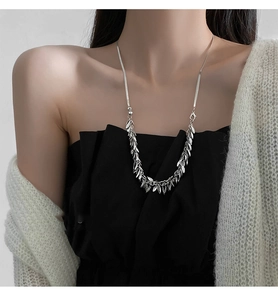 Detail of silver wheat-leaf tassel pendant necklace worn on neck with metallic fringe style