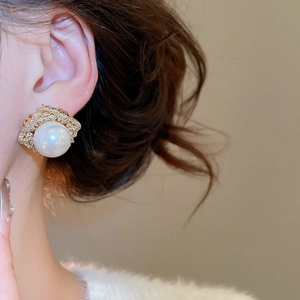 Detailed view of luxury gold stud earrings with large white pearl and zircon on model