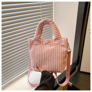 Close-up of pink corduroy mini bucket bag featuring soft plush handles and shoulder strap