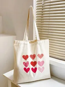 Chic cream canvas tote bag with nine red and pink heart prints on white tabletop