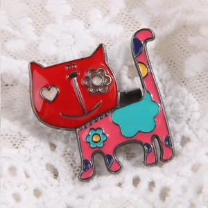 Detail of colorful enamel cat brooch with floral patterns on white lace fabric