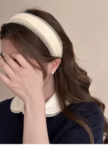 Detail of beige tulle headband and pearl earring on a model for an elegant hair accessory style
