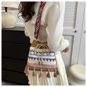 Detail of woven bucket bag featuring colorful embroidery tassels and patterned strap