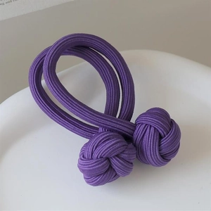Detail of high-elastic purple braided hair tie with durable knotted design on white tray