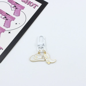 Detail of white enamel cowboy hat and boot keychain charms with gold star accents